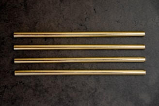 Close-up of shiny stainless steel straws arranged neatly on a wooden table.