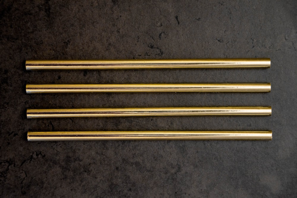 a group of four gold colored straws sitting on top of a table