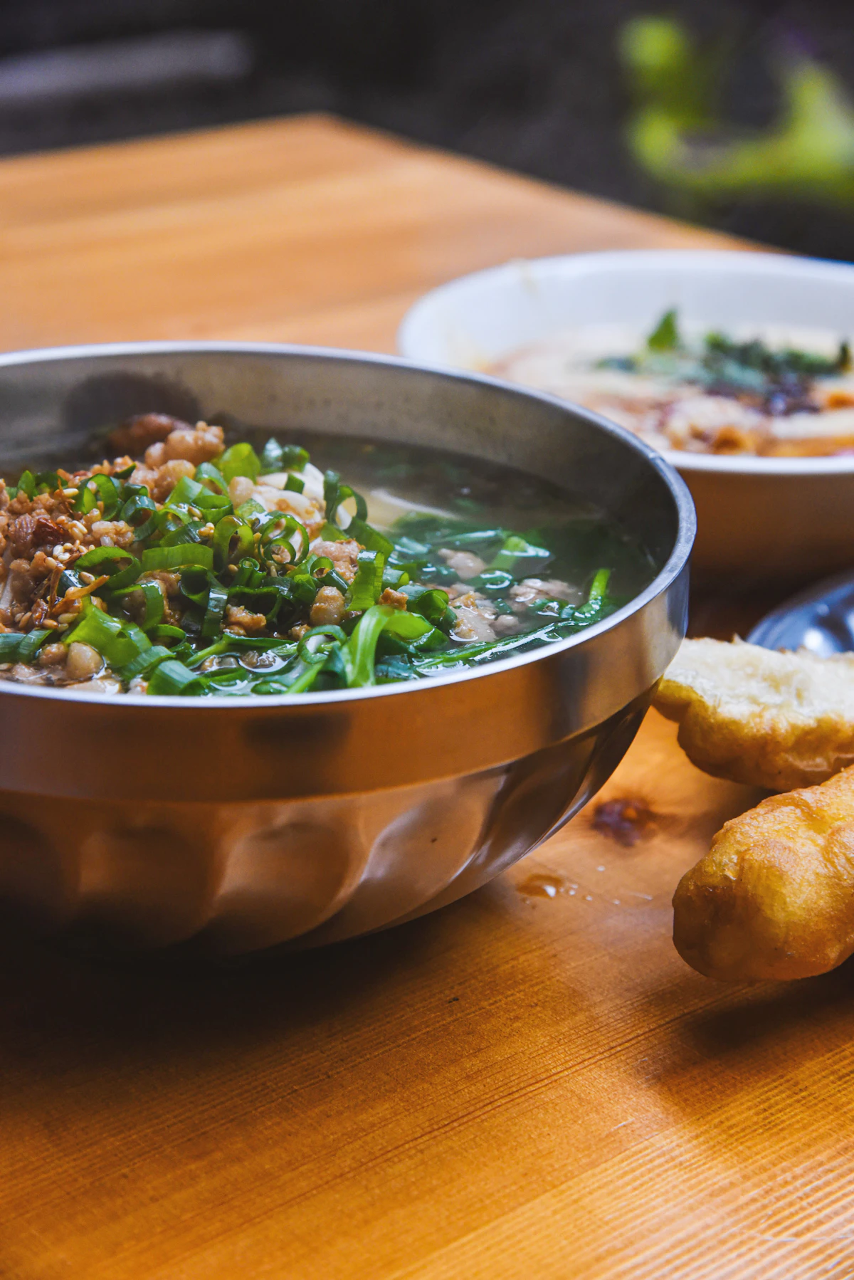 Bàn gỗ bày nhiều bát món ăn Hàn Quốc gồm canh, cơm và món phụ