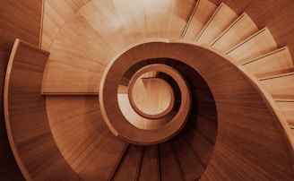 a wooden spiral staircase with a skylight in the background