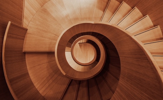a wooden spiral staircase with a skylight in the background