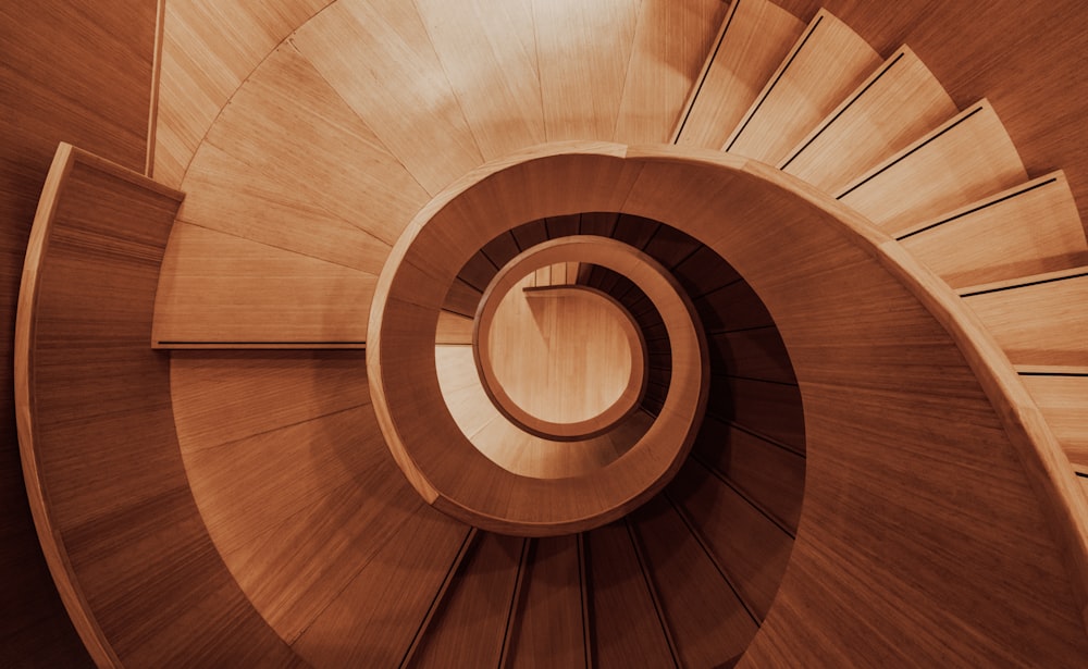 a wooden spiral staircase with a skylight in the background