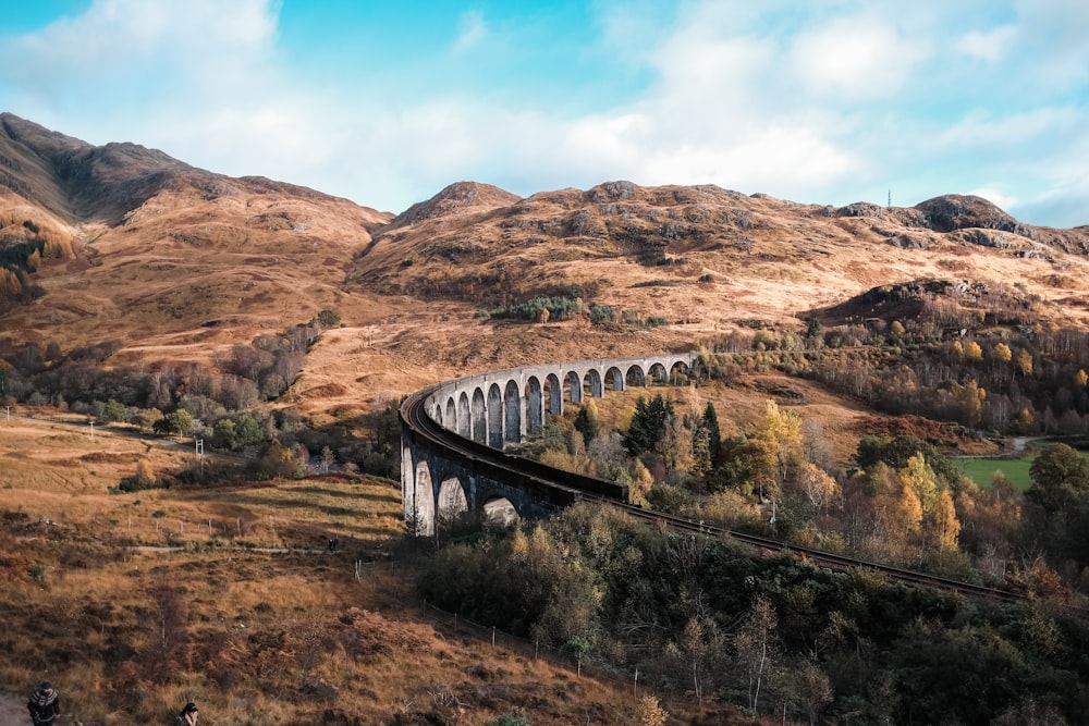 a train traveling over a bridge in the mountains