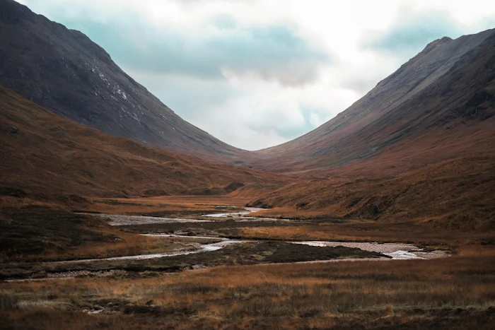 A green Highland valley with a stream and mountains