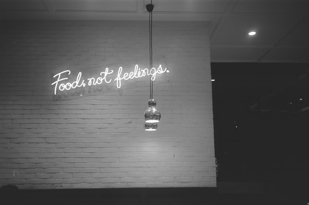 a brick wall with a neon sign that says food not feelings