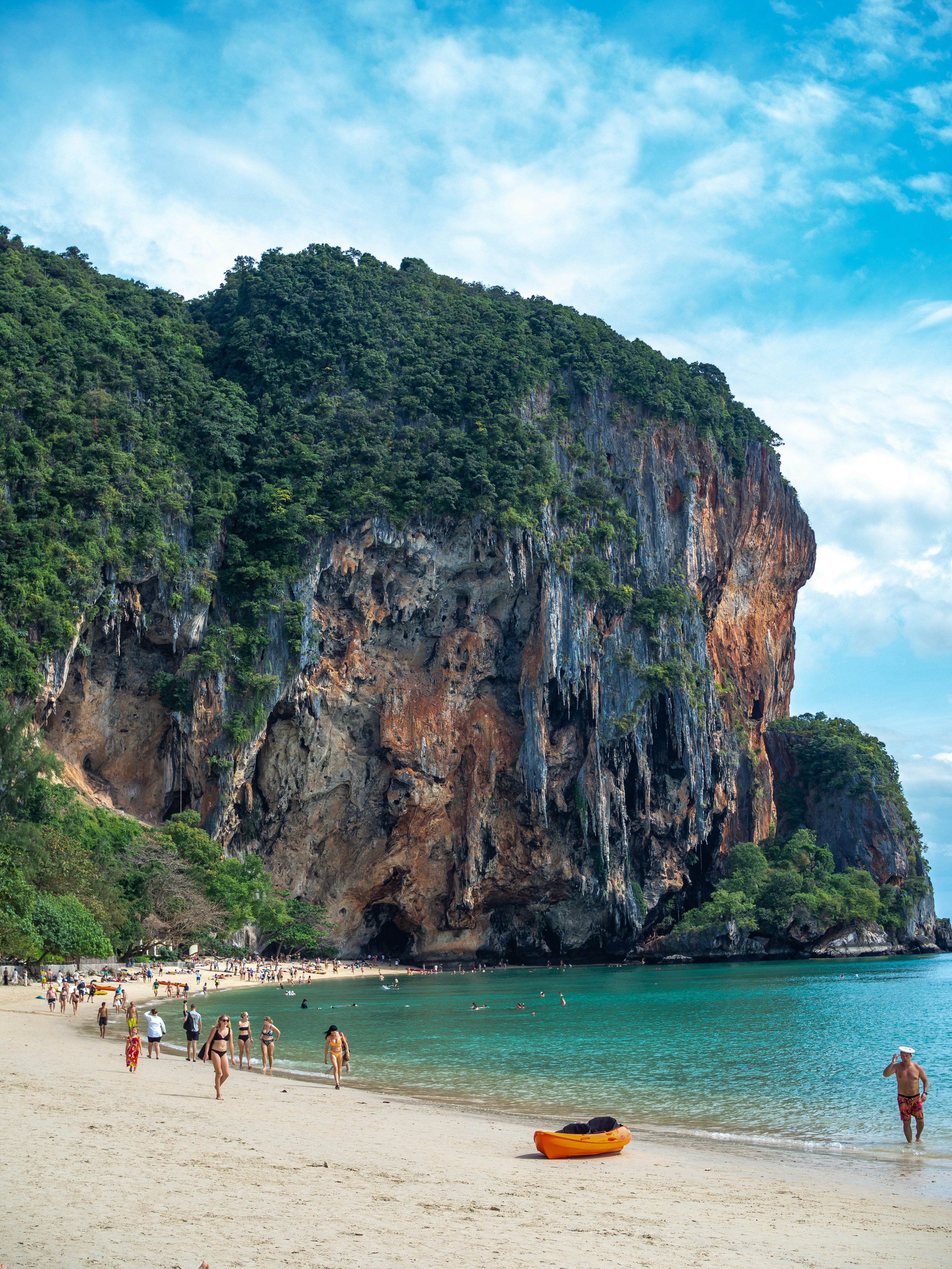 a group of people walking on a beach next to a mountain