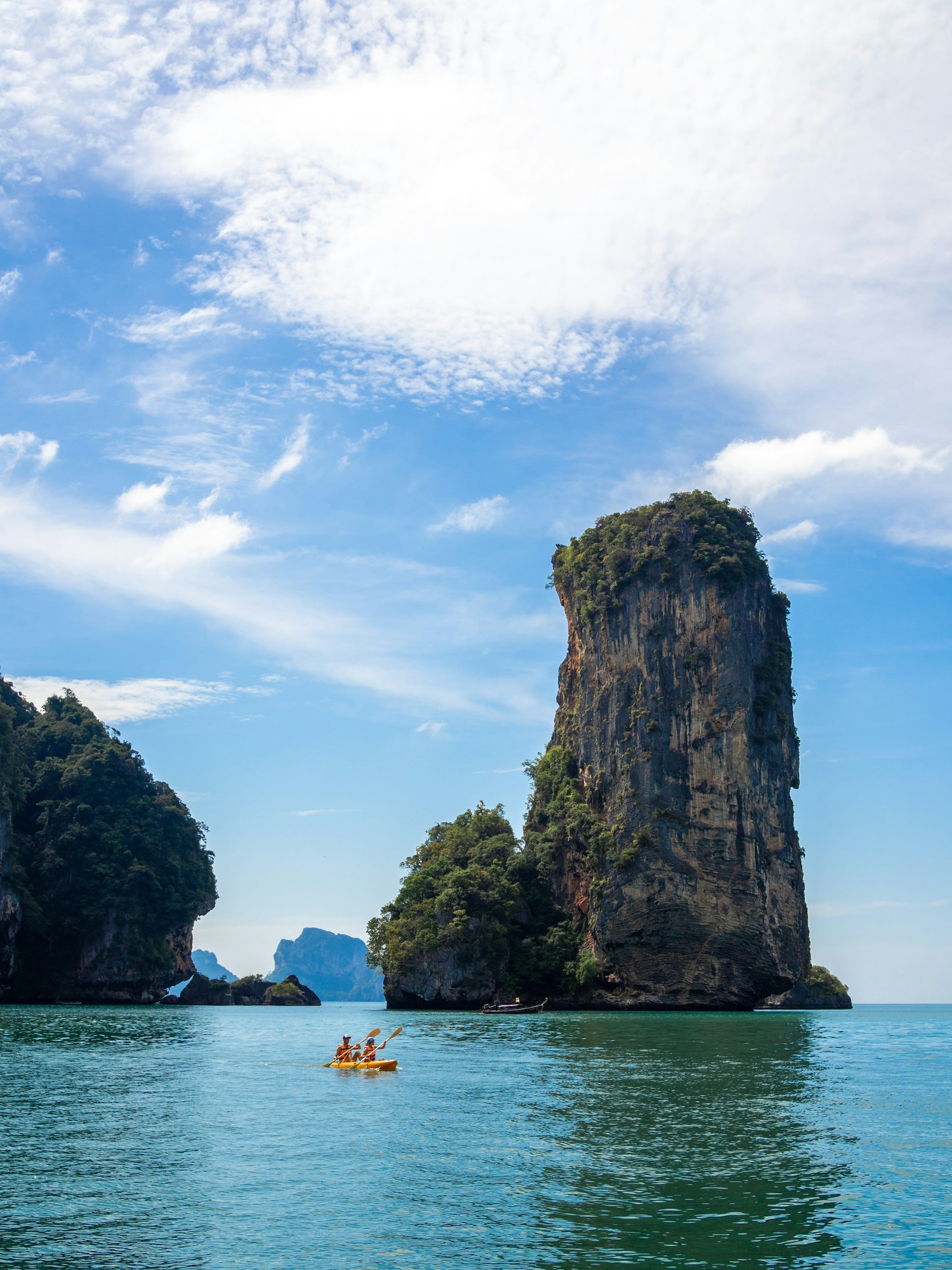 Adventurous travelers kayaking through the serene lagoons of Siargao, surrounded by towering cliffs.