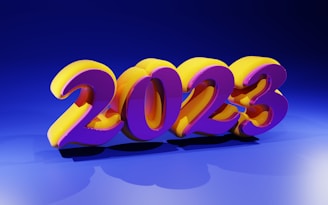 Bright and colorful 3D numbers displaying '2023' are prominently positioned in the center. The numbers are stylized with a vibrant purple and yellow color scheme, casting shadows on a blue background. The lighting creates a glossy and reflective effect on the numbers.