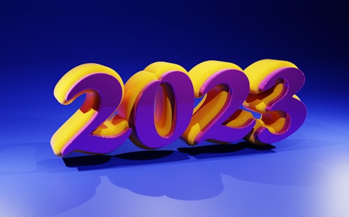 Bright and colorful 3D numbers displaying '2023' are prominently positioned in the center. The numbers are stylized with a vibrant purple and yellow color scheme, casting shadows on a blue background. The lighting creates a glossy and reflective effect on the numbers.
