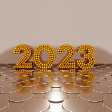 Golden numbers forming '2023' are made of spherical elements and stand upright on a reflective, circular pattern surface, set against a plain beige background.
