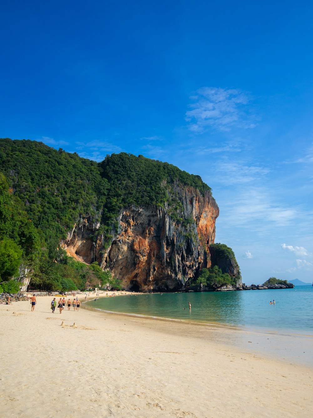 a beach with people walking on it and a mountain in the background