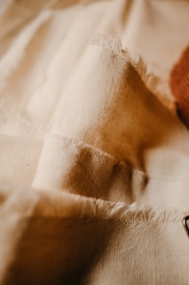 Close-up of a beige dress fabric with fine texture and elegant stitching, evoking softness.