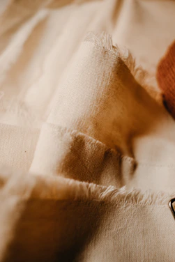 Close-up of luxurious beige linen fabric with delicate embroidery, evoking warmth and craftsmanship.