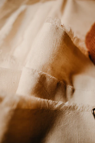 Close-up of delicate embroidered patterns on soft beige unstitched fabric.