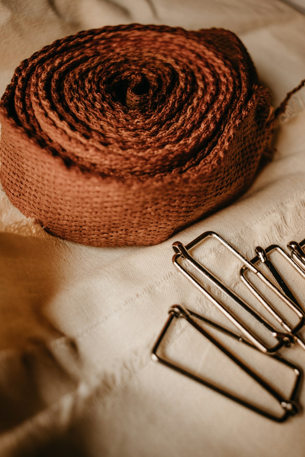 a roll of twine sitting on top of a bed next to a pair of