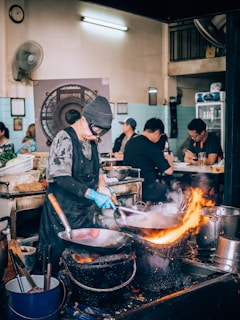 a man cooking food in a kitchen on top of a stove