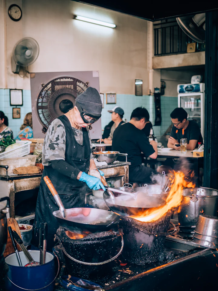 A cook stir-frying food in a wok