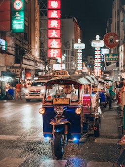 a small car driving down a city street at night