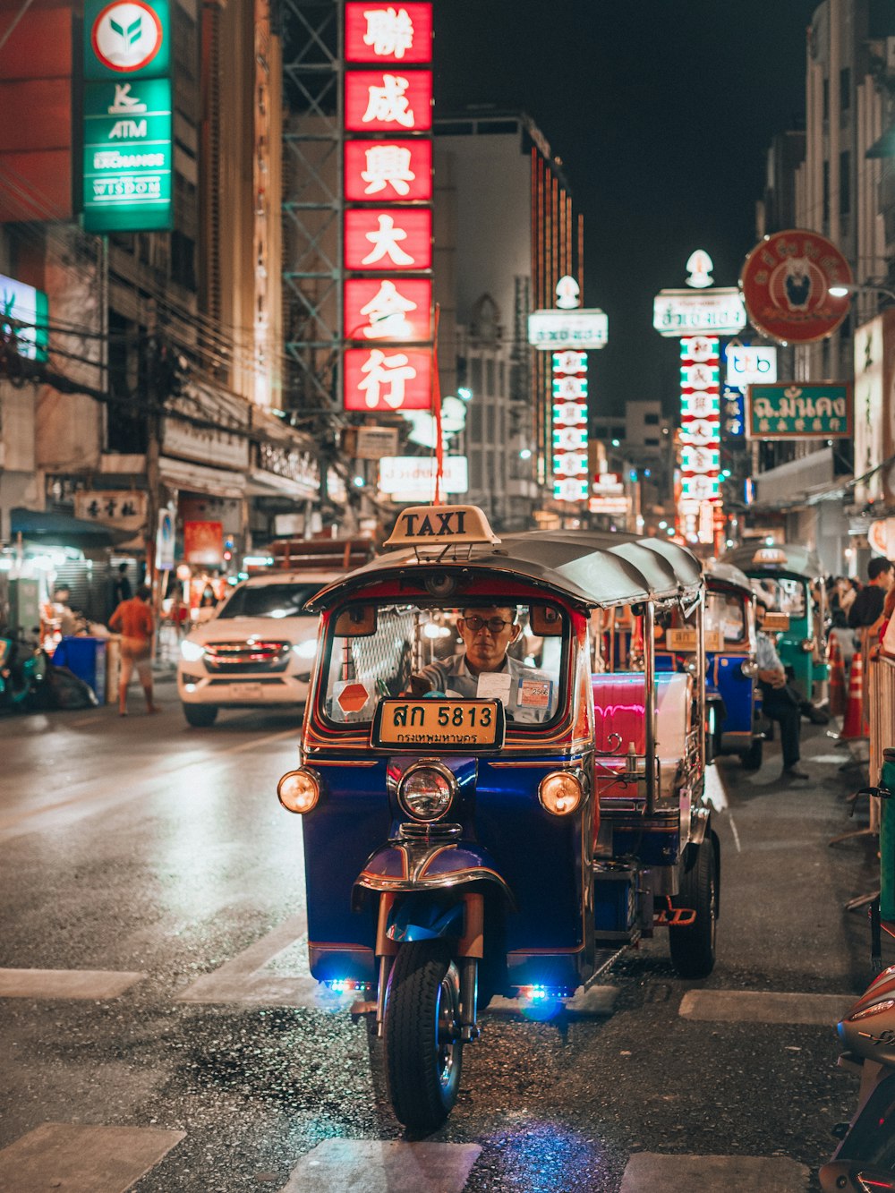 a small car driving down a city street at night