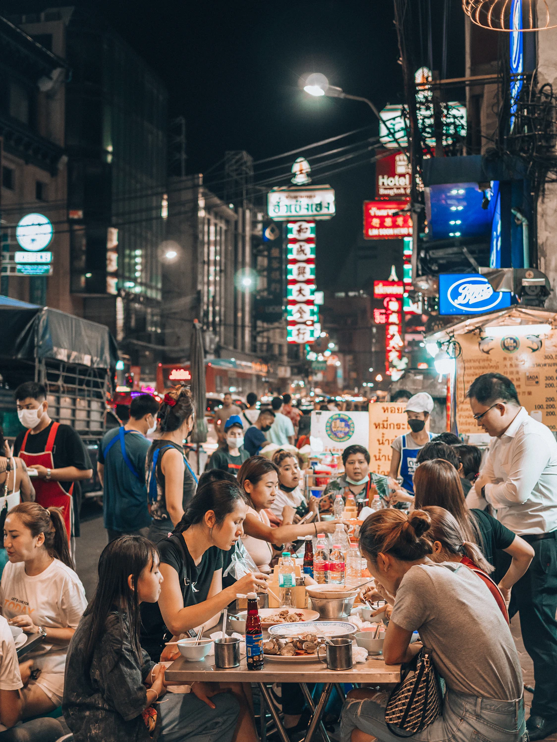 a group of people sitting at a table in the middle of a street