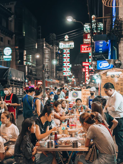 a group of people sitting at a table in the middle of a street