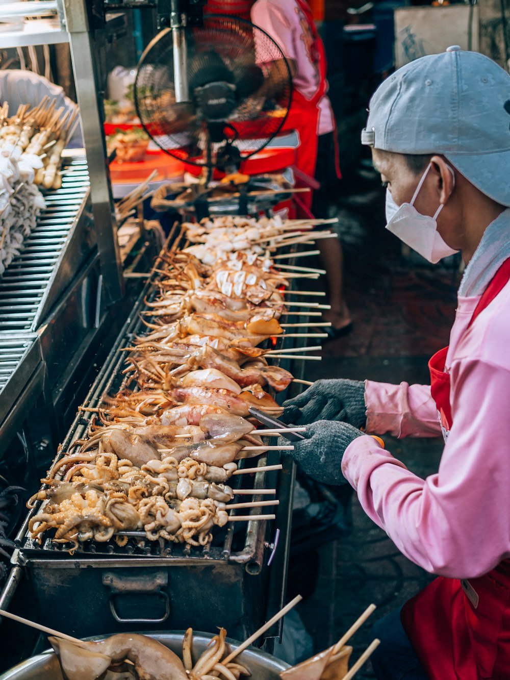 a person wearing a mask cooking food on a grill
