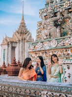 two women standing next to each other in front of a building