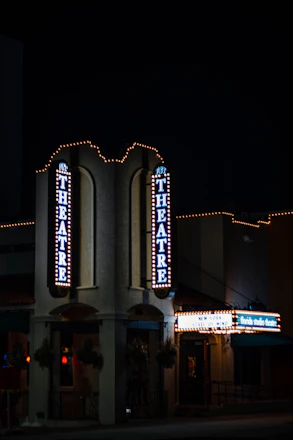 An inviting theater lobby with classic marquee lights glowing softly in the evening.