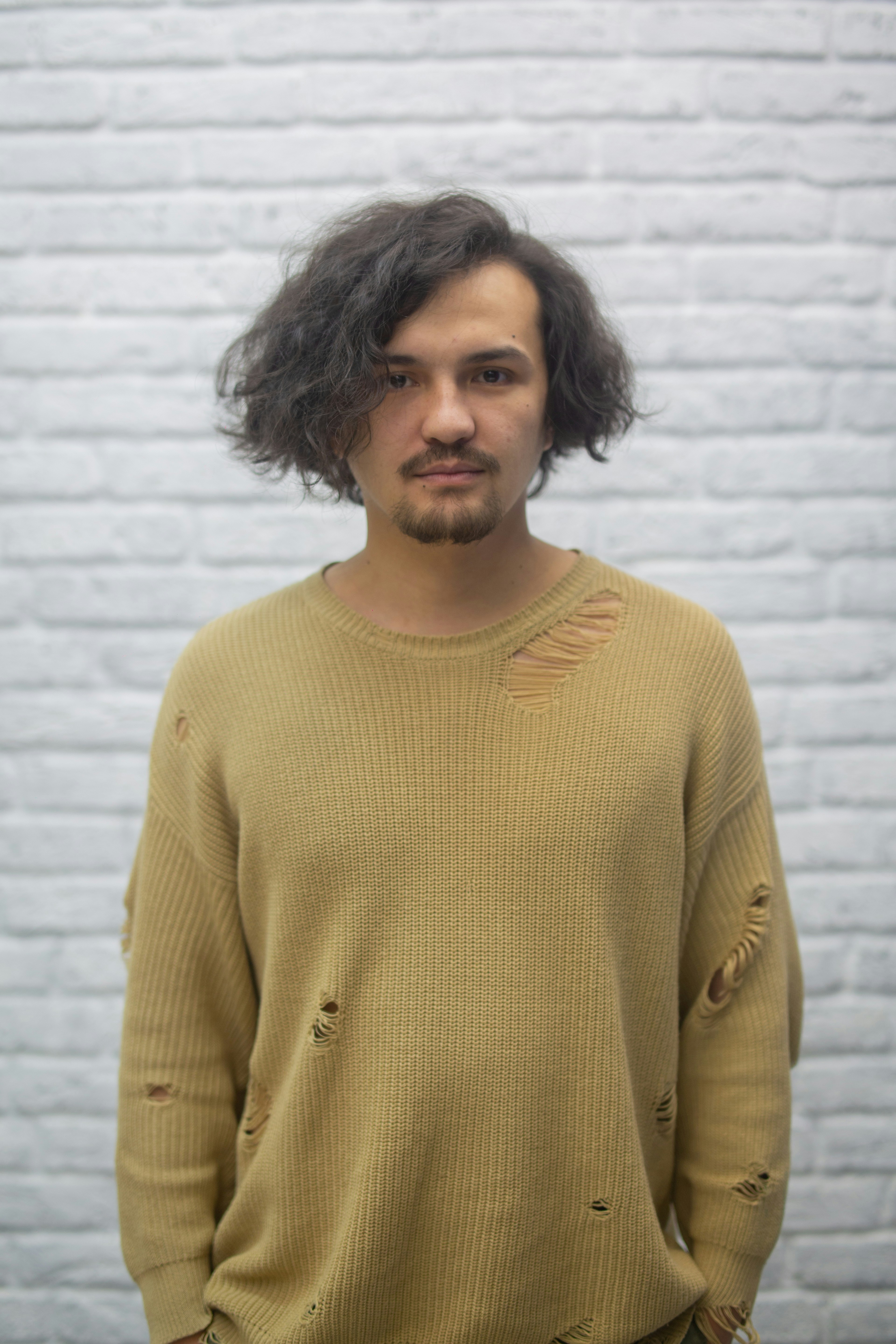 a man standing in front of a white brick wall