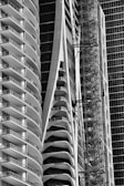 Tall, modern buildings with curved balconies and glass facades dominate the image. A construction scaffold is visible alongside one structure, suggesting ongoing development. The architectural design showcases sleek and futuristic aesthetics.