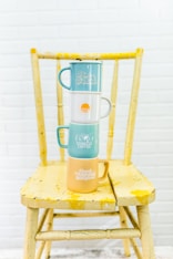 a stack of coffee cups sitting on top of a wooden chair