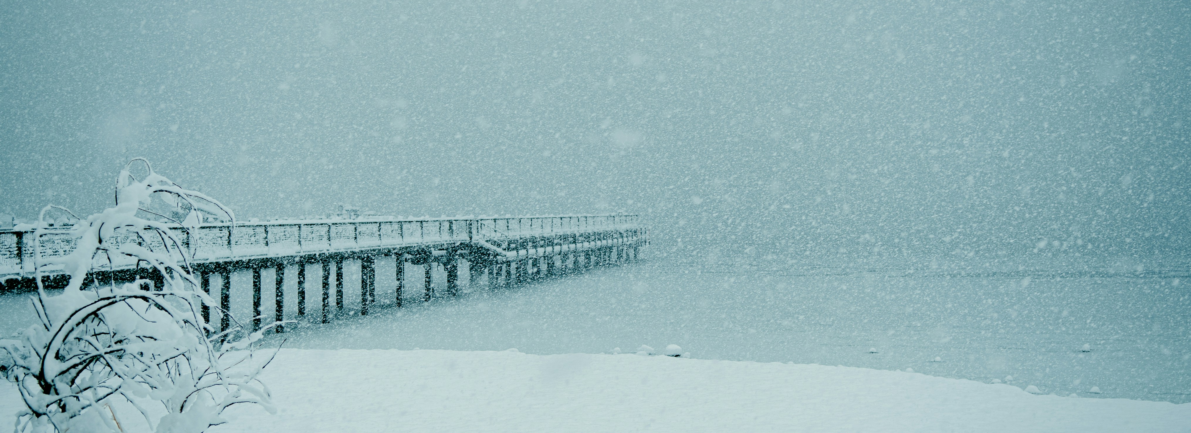 a snow covered pier on a snowy day, 
