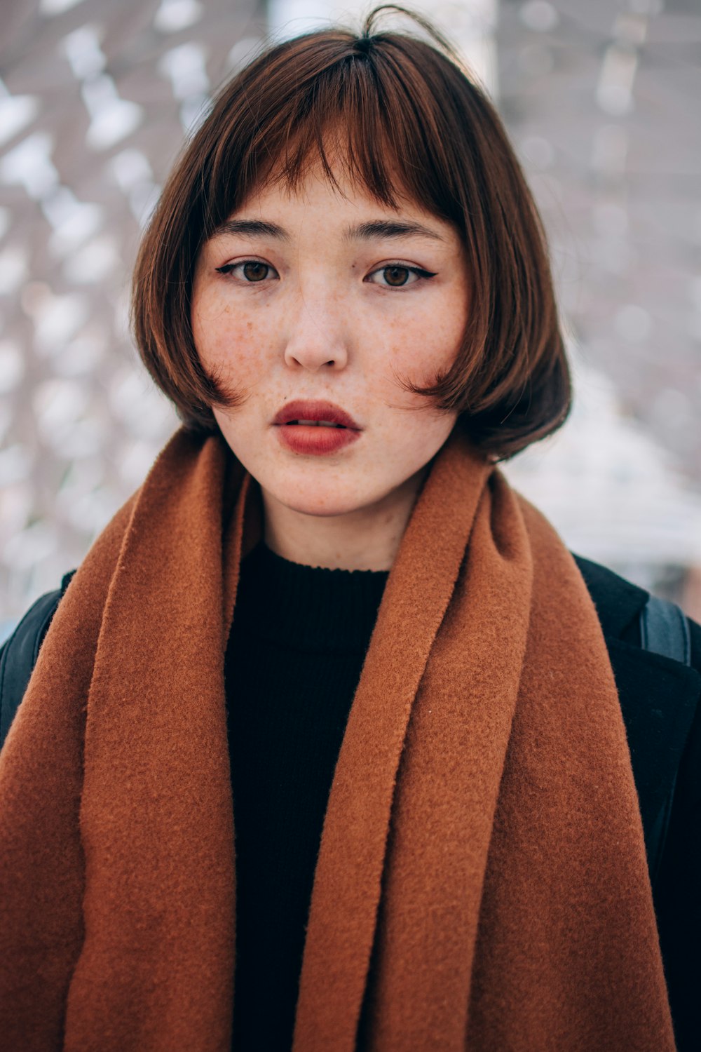 a woman with freckled hair wearing a brown scarf