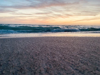 Sunset over a sandy Andalusian beach with gentle waves and a hint of orange sky.