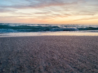 A tranquil scene of turquoise waves gently touching the golden sand at sunset.