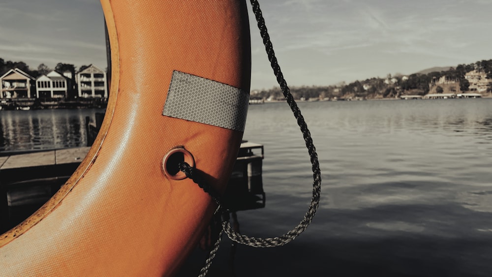 an orange life preserver sitting on the side of a body of water