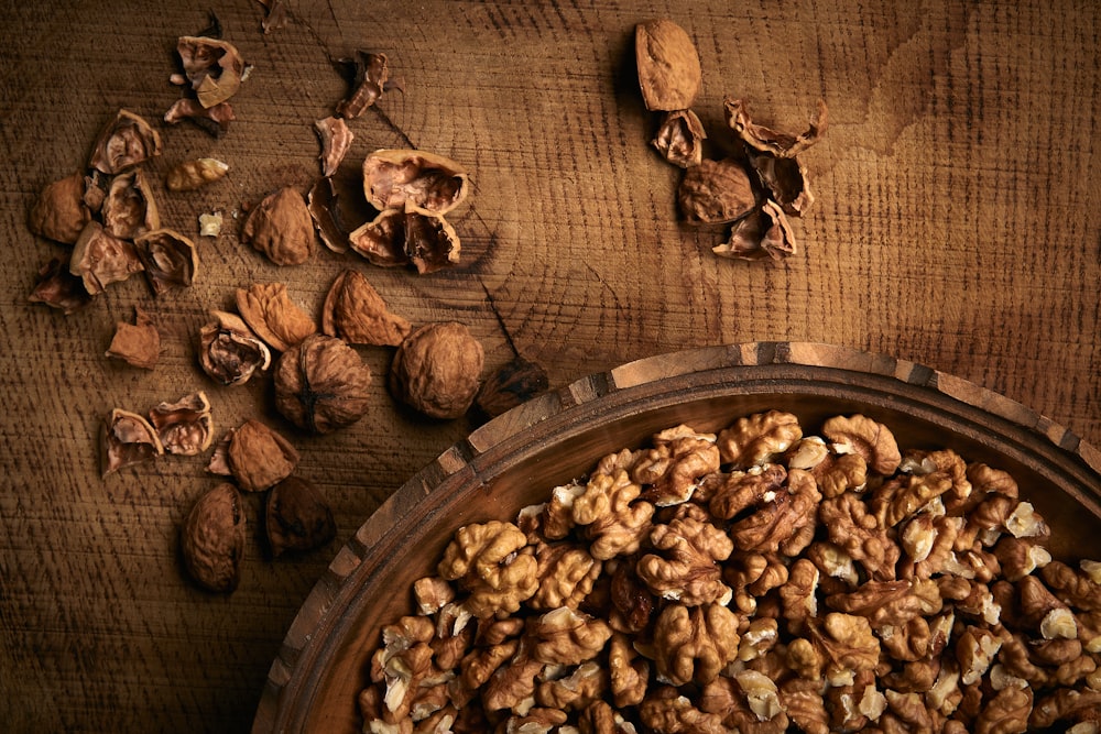 a wooden bowl filled with nuts on top of a table