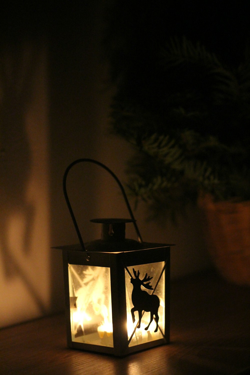 une lanterne allumée posée sur une table en bois