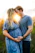 a pregnant couple kissing in a field at sunset