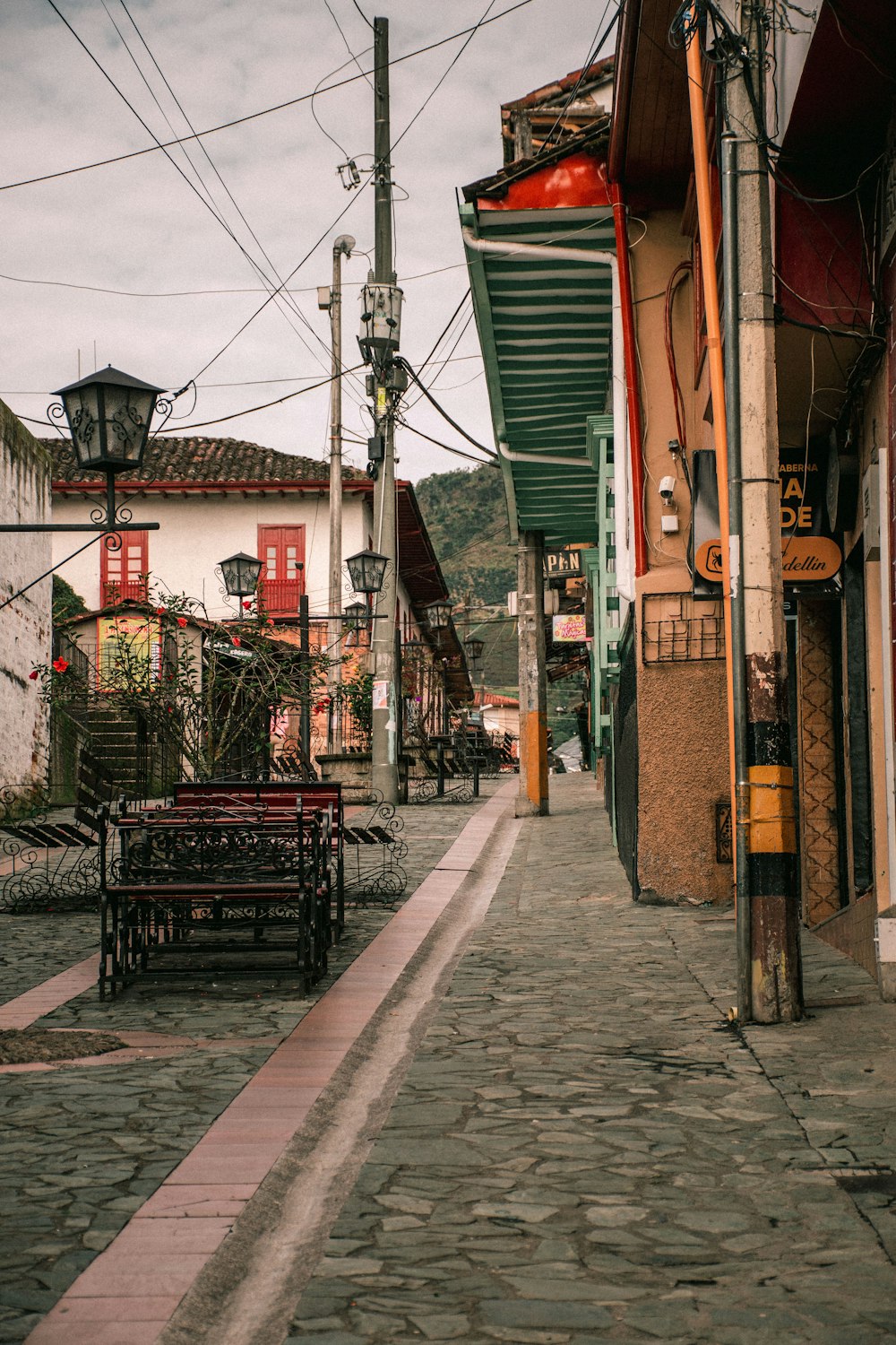 a cobblestone street lined with buildings and benches