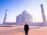 A joyful traveler standing in front of the Taj Mahal at sunset.