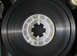 Close-up of tangled magnetic tape reels illuminated by eerie green light in a dark, cluttered lab.