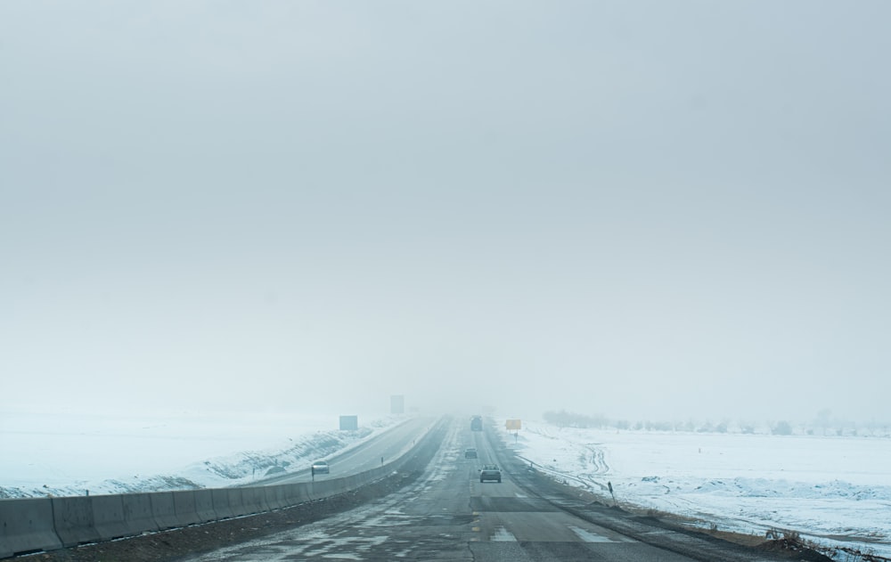 a foggy road with a car driving on it