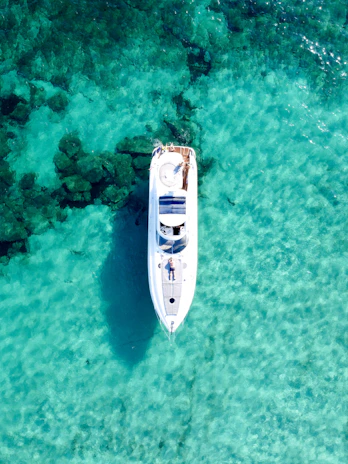 Aerial view of a yacht cutting through the emerald waters near the rocky coves of Urla.