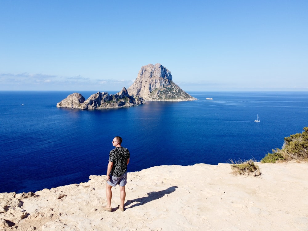 Ein Mann steht auf einer Klippe mit Blick auf den Ozean