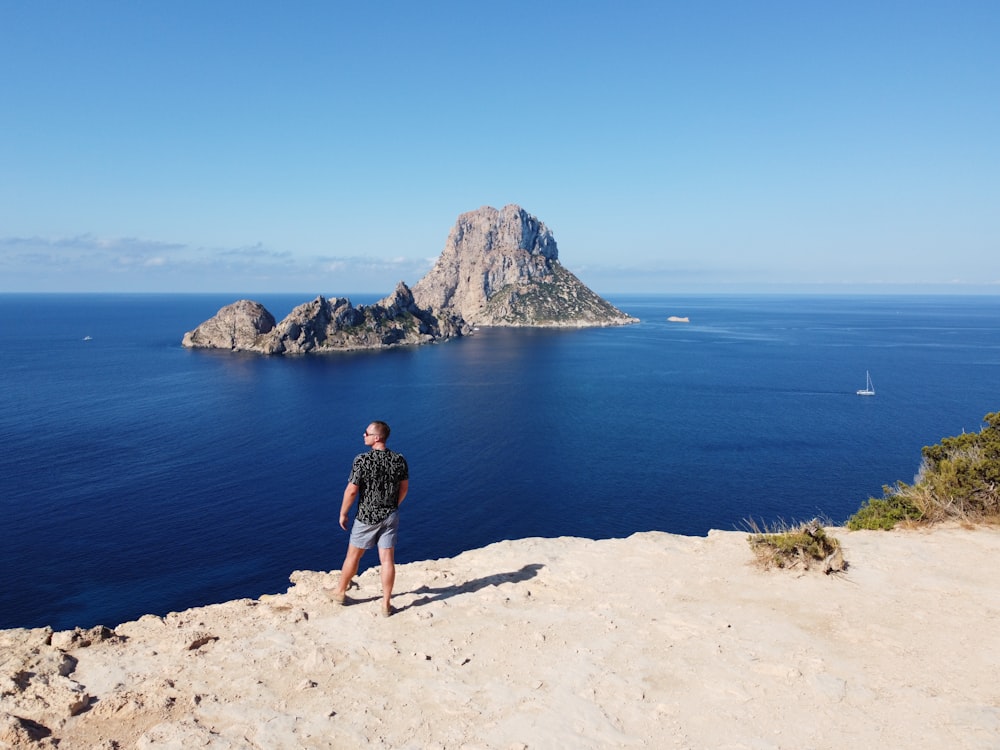 Un hombre parado en la cima de un acantilado junto al océano