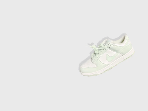 Minimalist white sneaker with clean lines displayed against a light gray background.