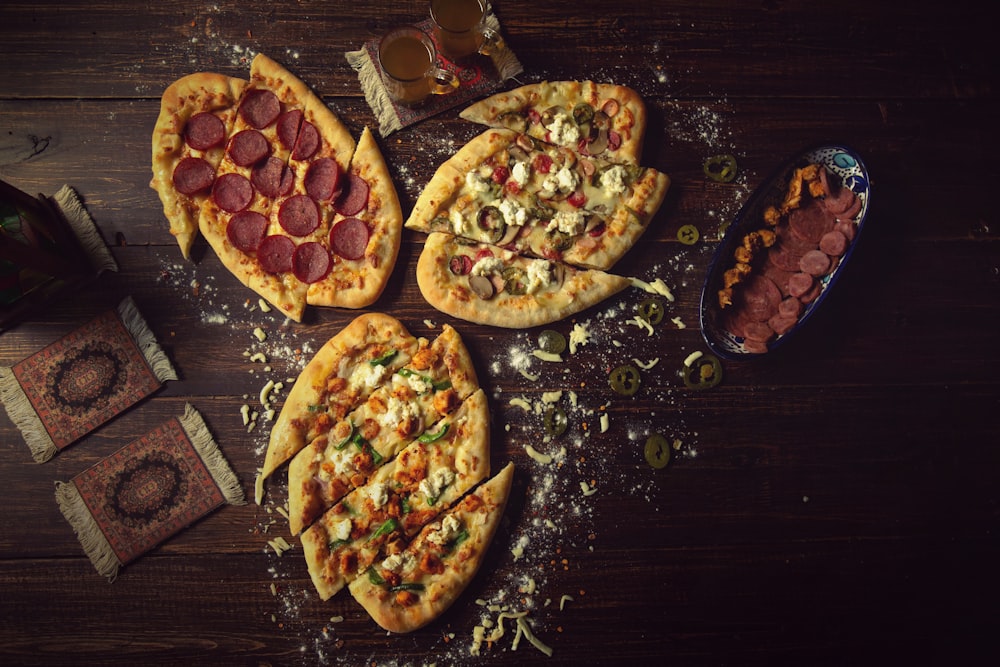 a group of three pizzas sitting on top of a wooden table