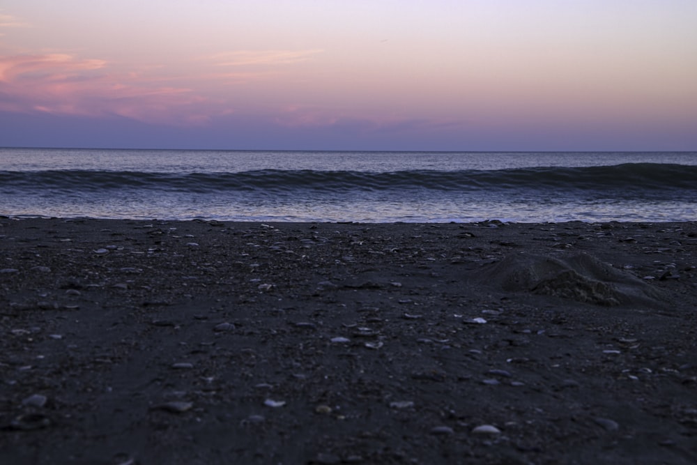 a view of the ocean from a beach at sunset