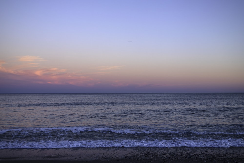 a view of the ocean from a beach at sunset